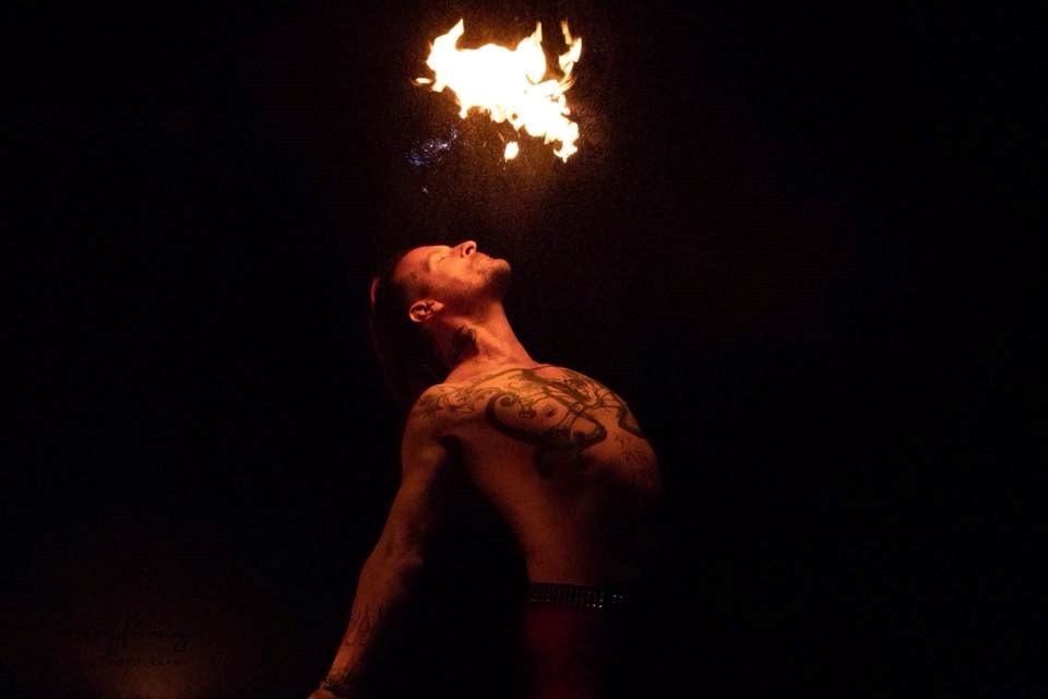 Fire performer breathing flames into the night sky during an outdoor performance at the fair.