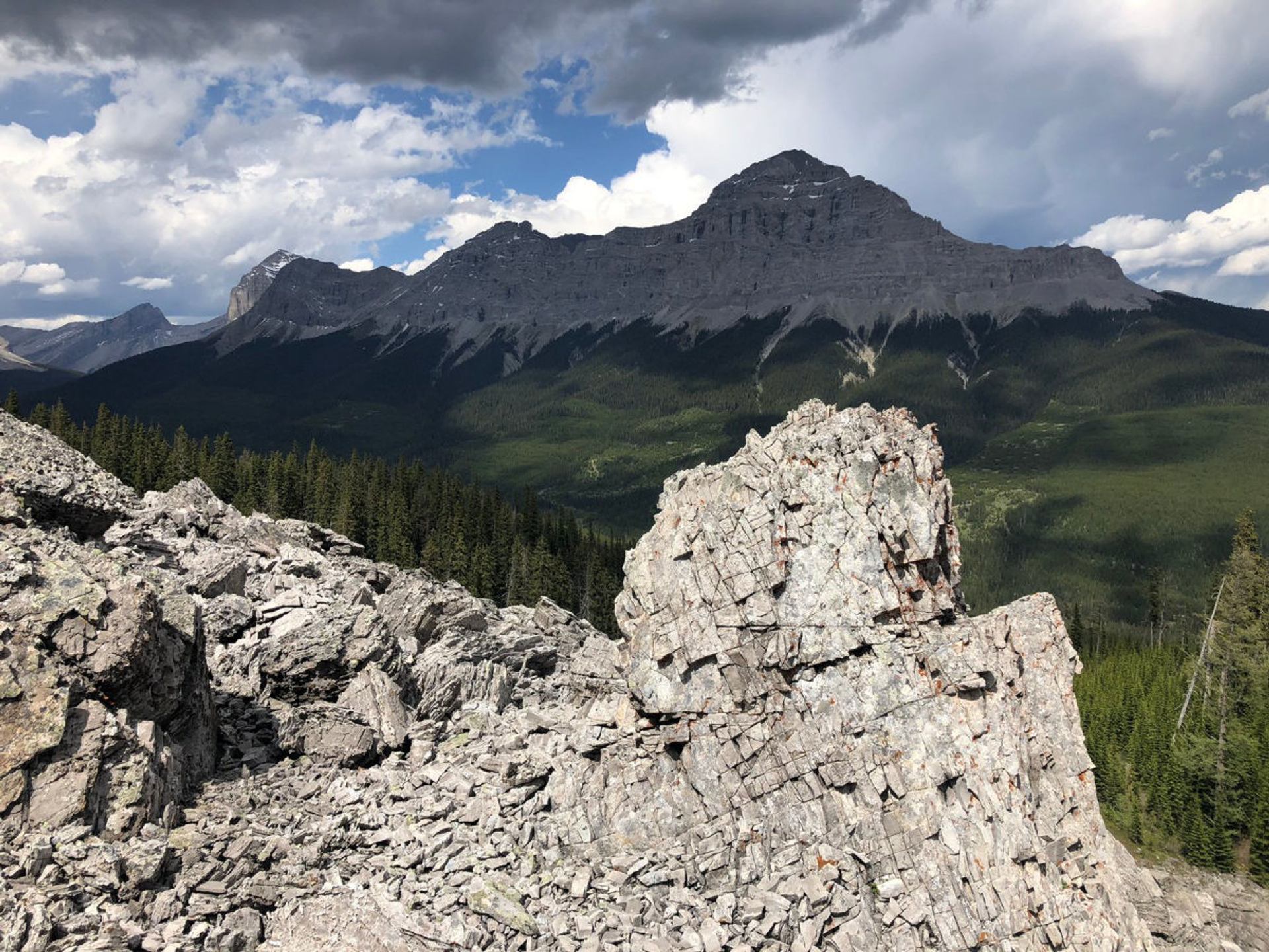 Jagged rock outcrops overlooking forested valleys and layered mountain peaks.