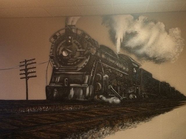 Black and white mural of a steam train on tracks with smoke rising, surrounded by electrical poles.
