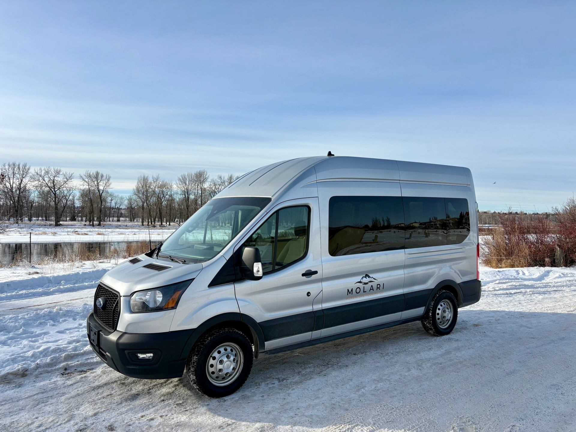 MOLARI tour van parked on a snowy roadside under a clear winter sky.