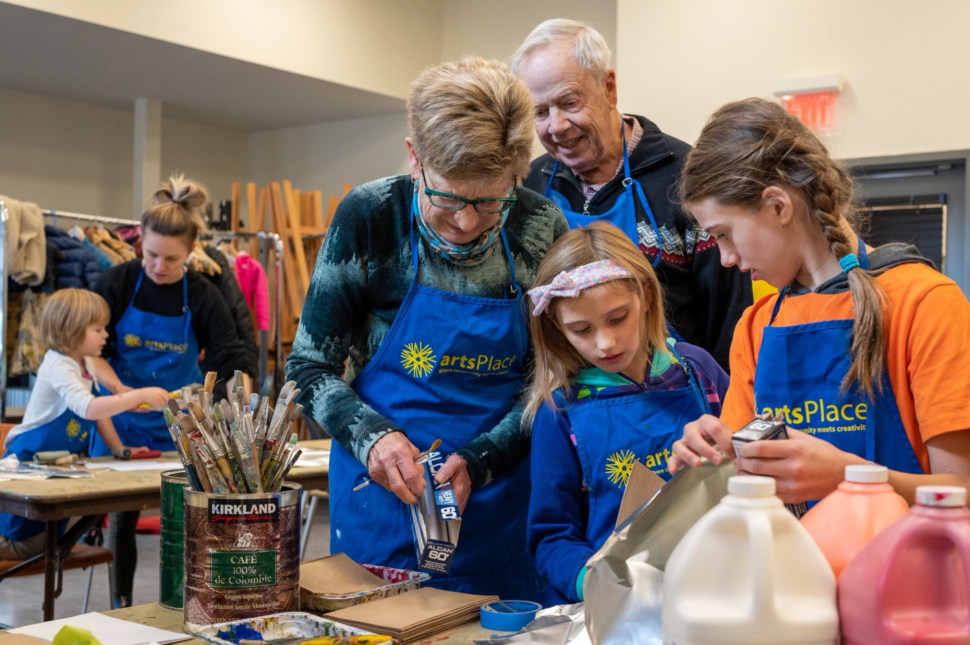 A family works on a craft together in a brightly lit studio.