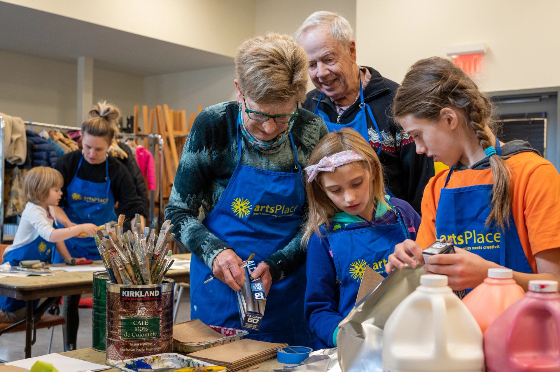 A family works on a craft together in a brightly lit studio.