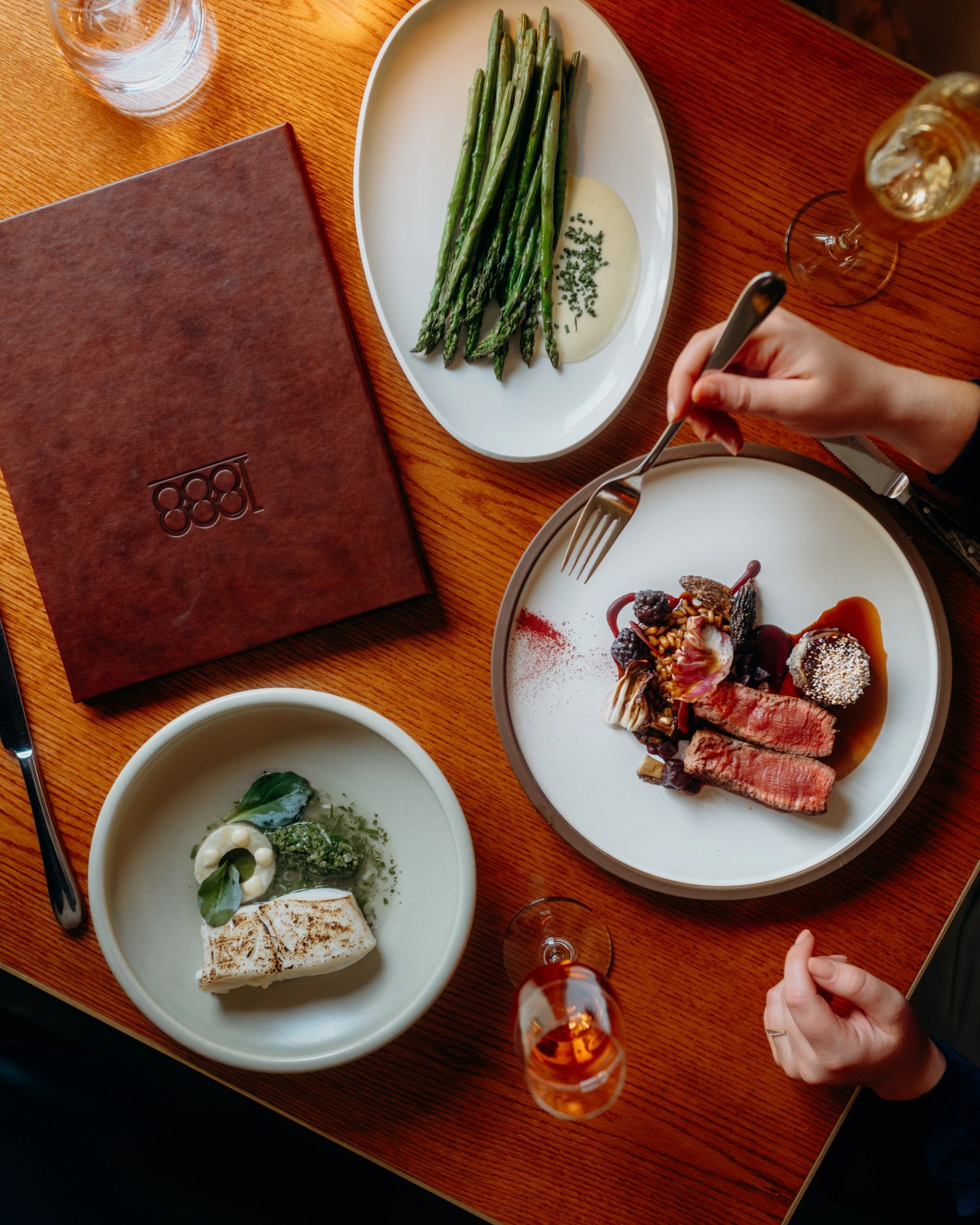 Plated steak and seafood dishes at 1888 Chop House with asparagus and elegant table setting.