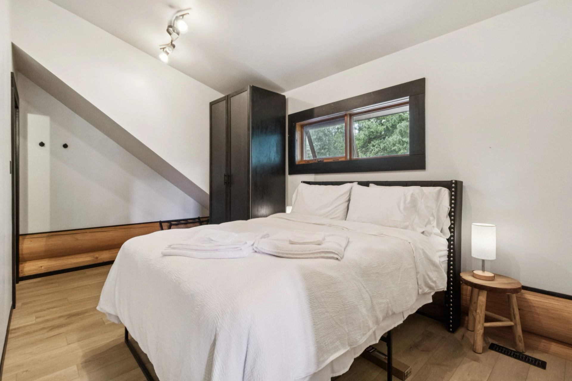 Minimalist bedroom with white linens and wood accents.