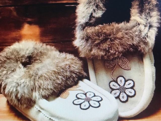 Pair of furry winter boots with flower appliques and dark laces on display.