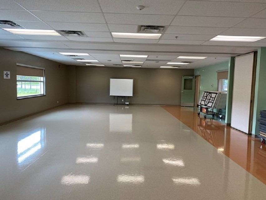 Empty community hall with polished floor, projector screen, and doors, inside Beaverlodge Recreation.