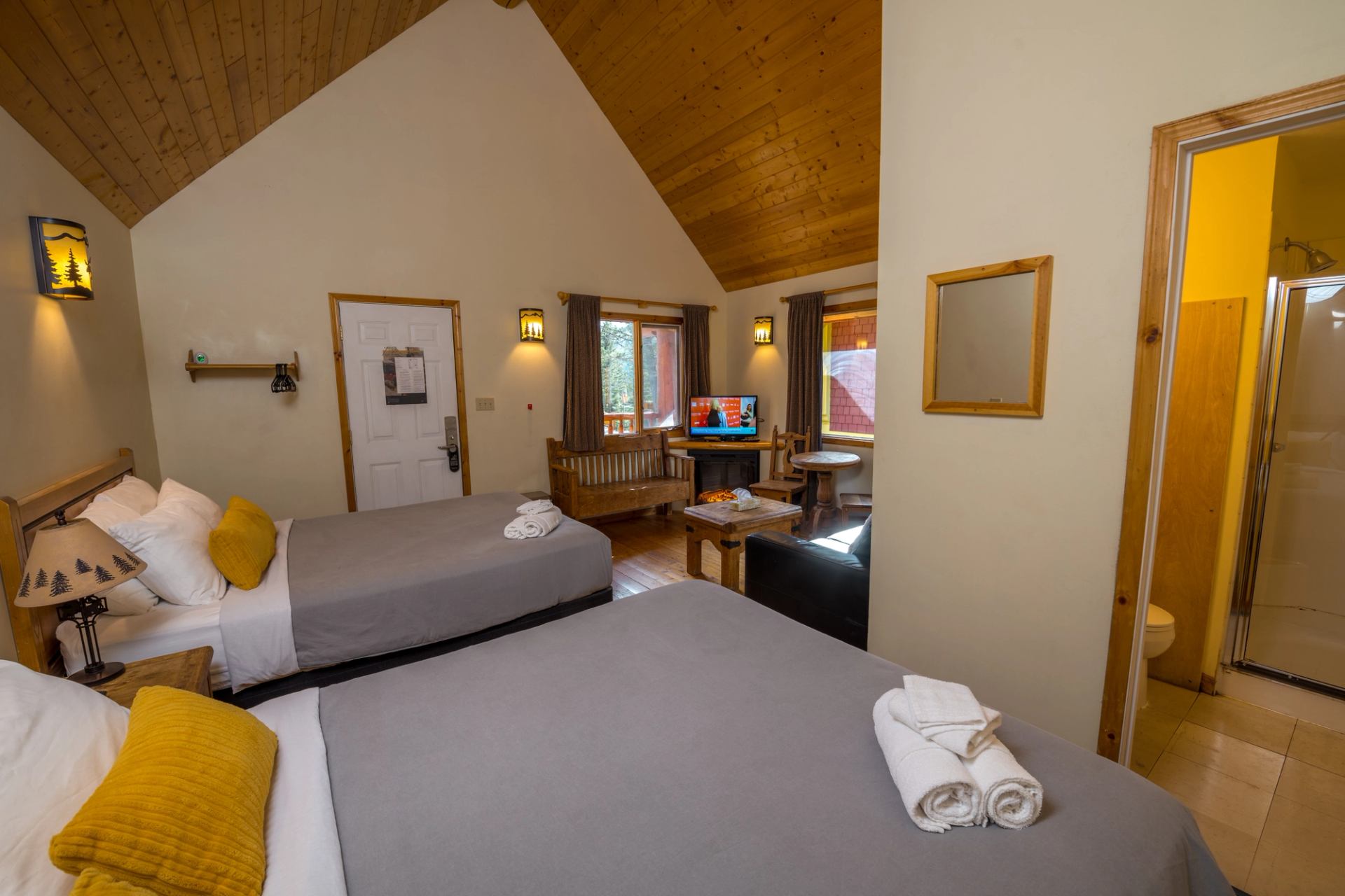 Private cabin with two beds, wooden ceiling, and seating area at HI Banff Alpine Centre.