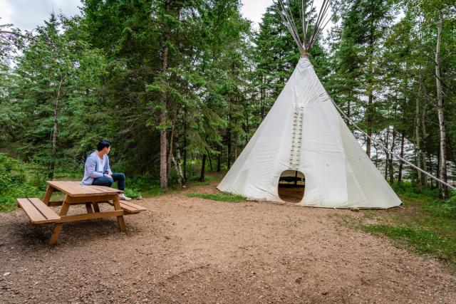 Women sitting on picnic table outside of tipi at Elk Island Retreat.