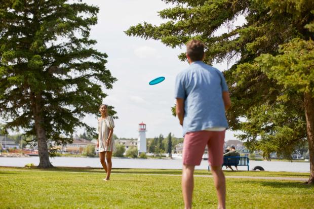 A couple play frisbee in a park at Sylvan Lake.