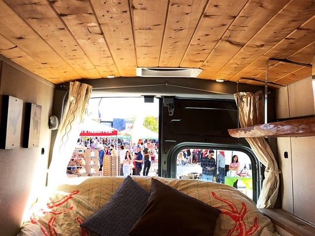 Cozy campervan interior with wood finish and market view.