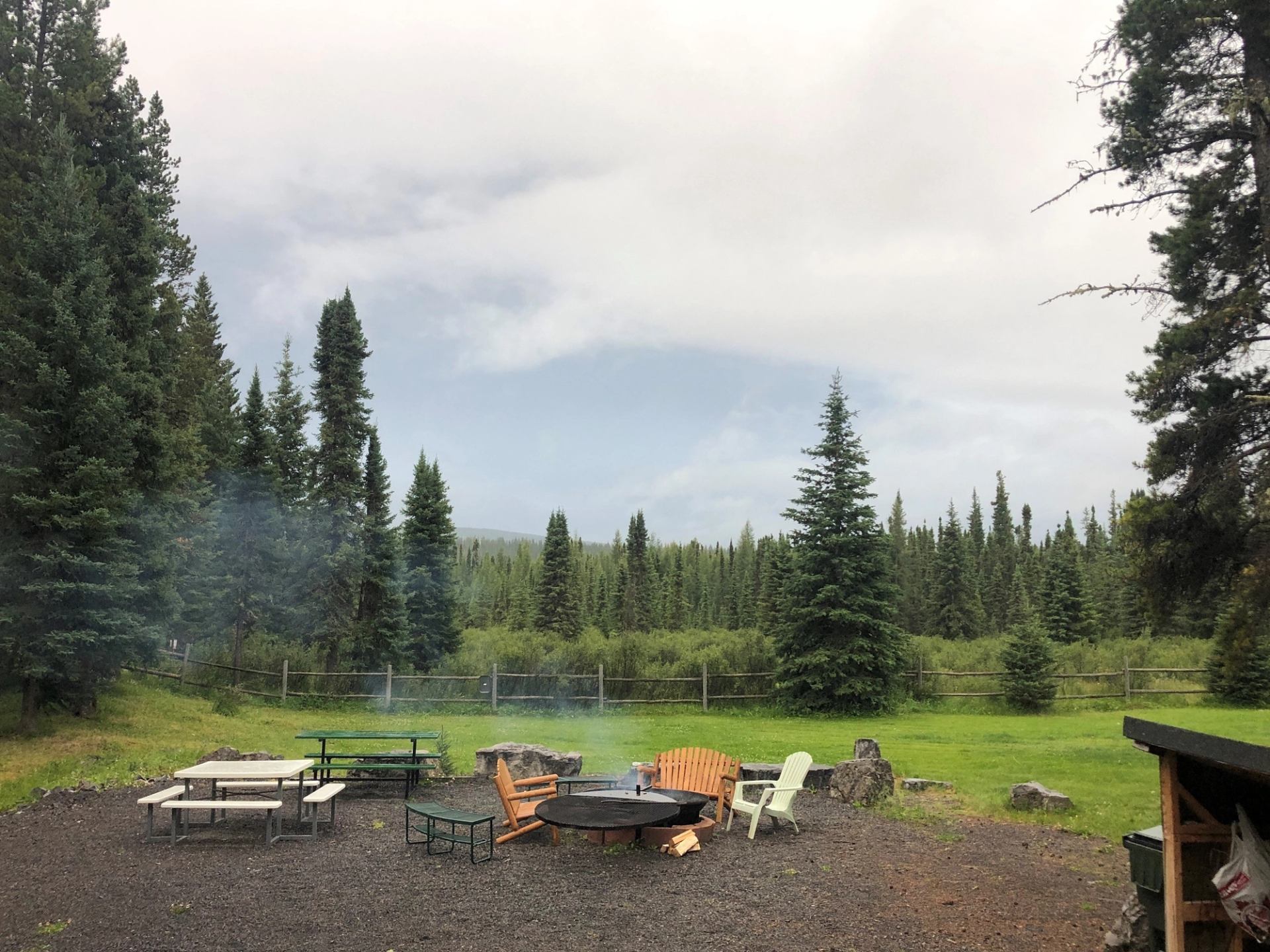 Smoky fire pit with seating in forest clearing at Cheechako Cabins.