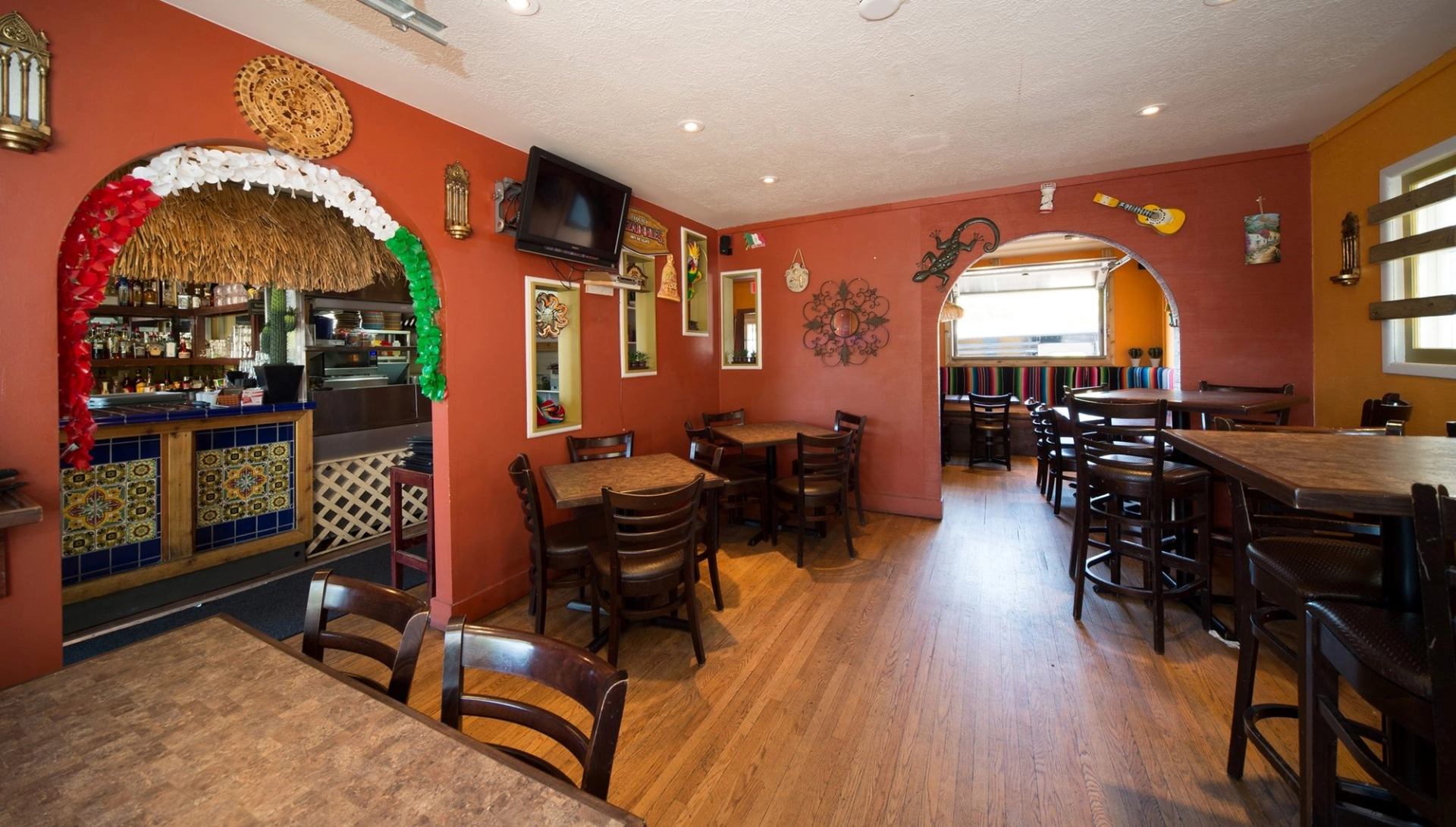 Cozy dining area with vibrant orange walls and Mexican-themed decor at Los Chilitos.