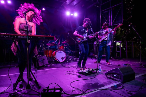 Alex Macneil and the Revenants perform on ATB Stage. The band is lit by intense purple lighting as they jam out.