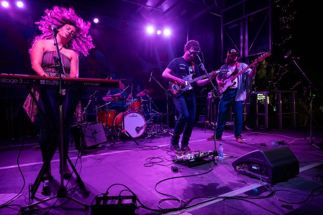 Alex Macneil and the Revenants perform on ATB Stage. The band is lit by intense purple lighting as they jam out.