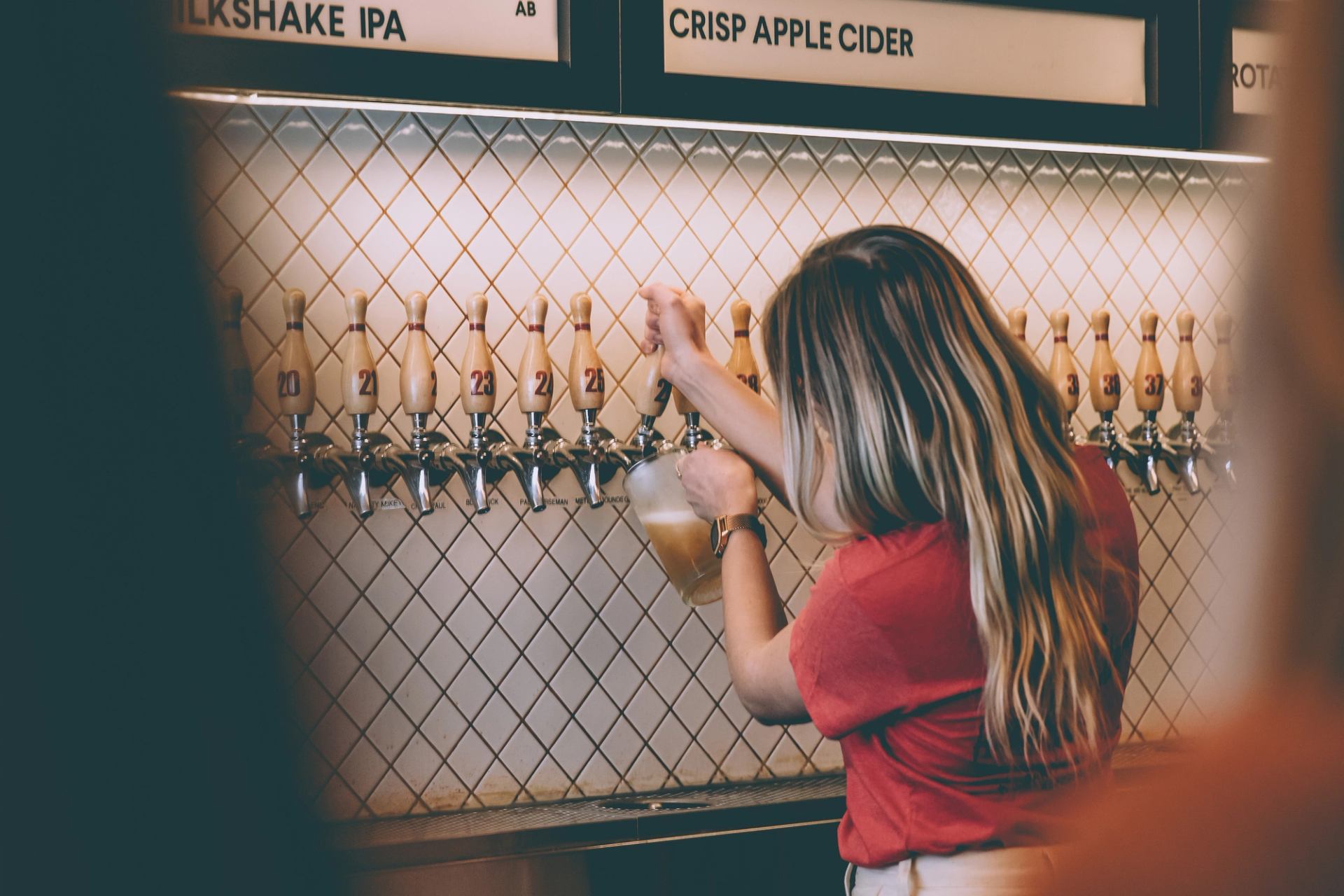 A bartender pours a pitcher of beer from one of the 48 taps.
