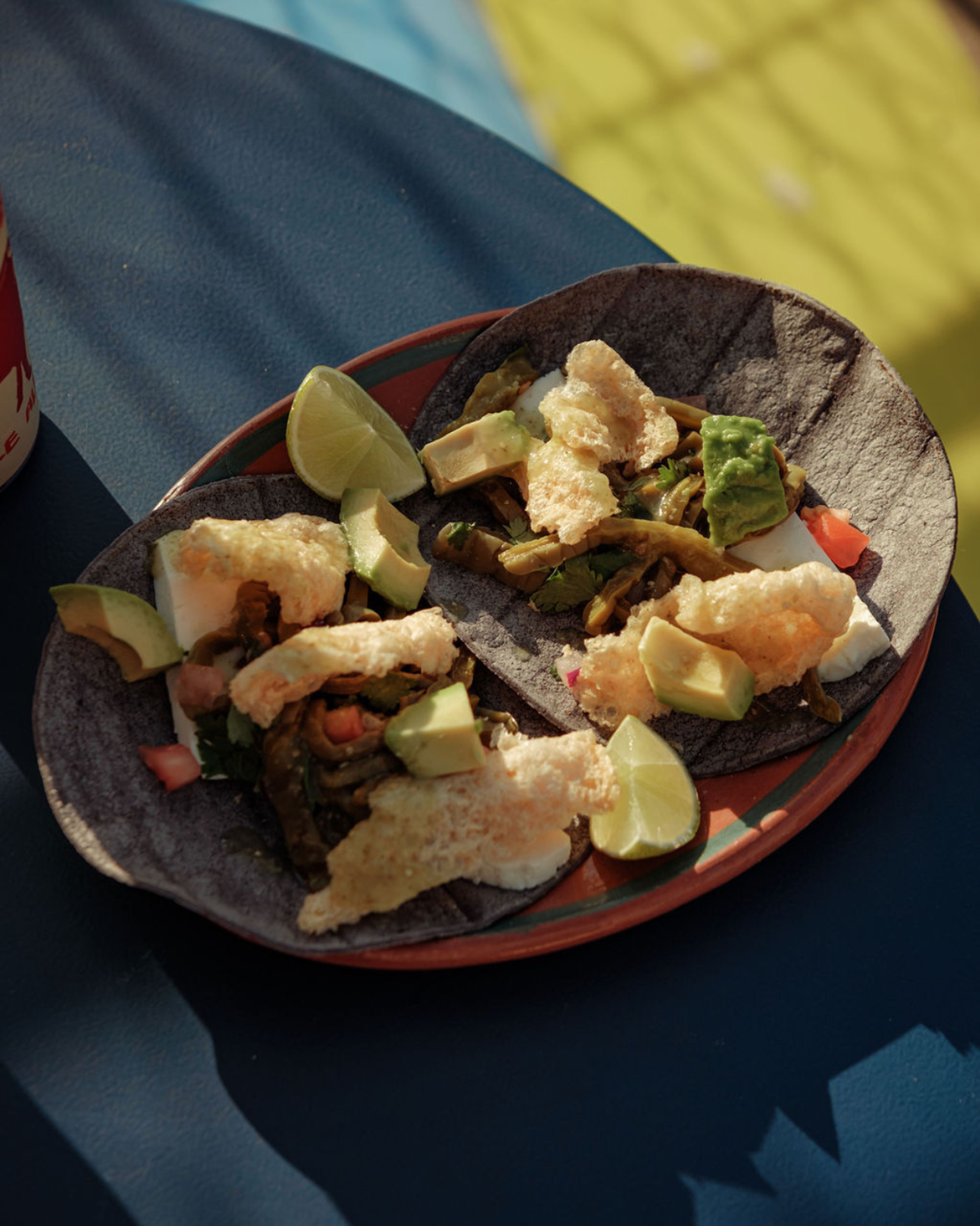 Blue corn tacos with avocado and grilled veggies on outdoor table.