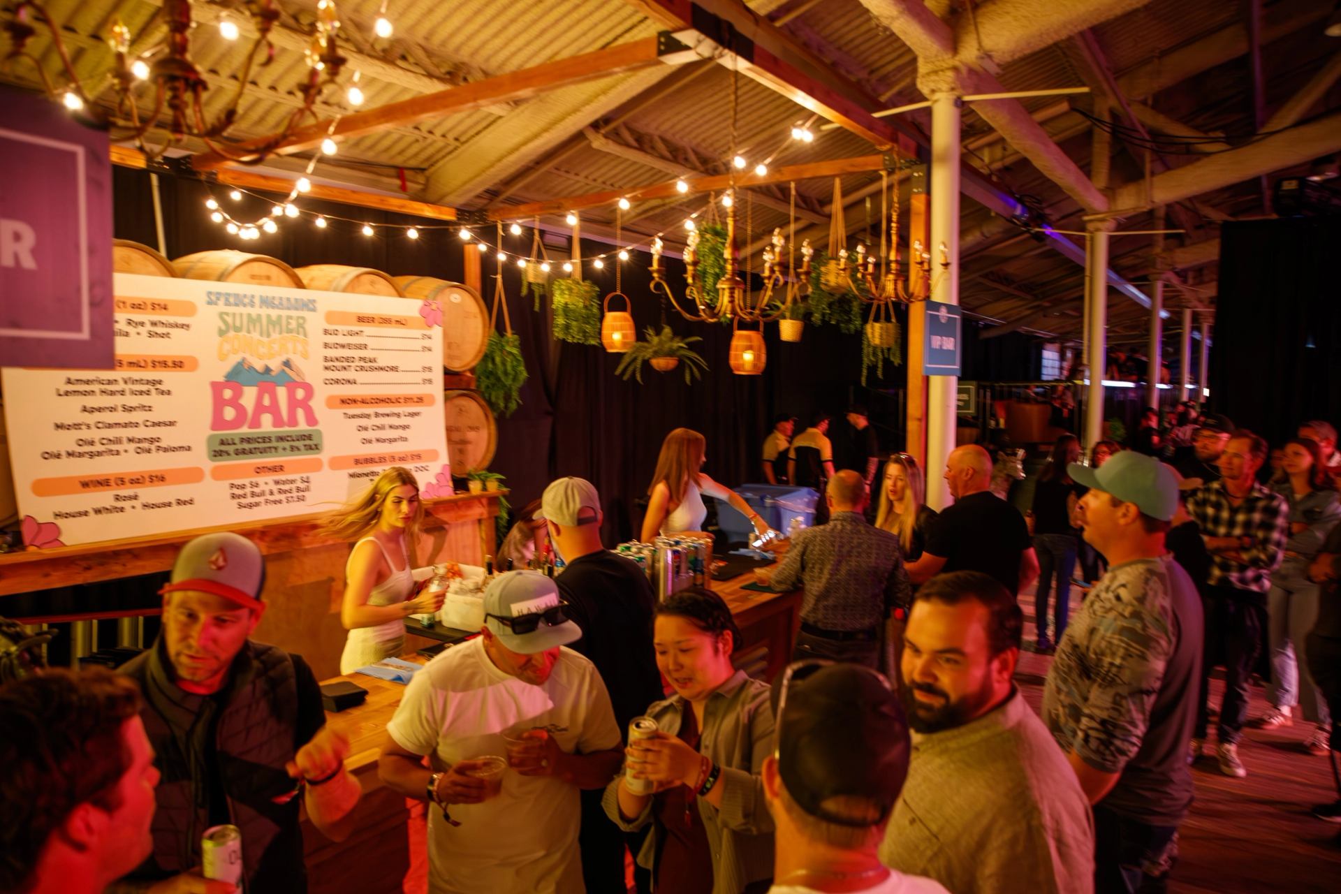 Crowd orders drinks at a warmly lit bar inside the venue.