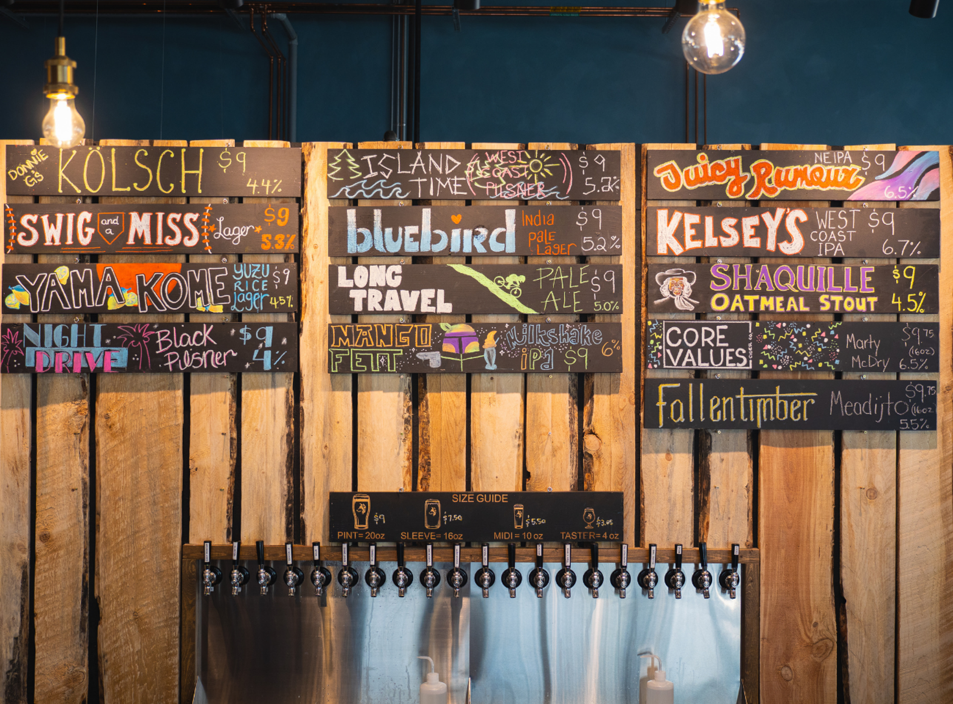 Colourful chalkboard beer menu hangs above taps on a rustic wooden wall.