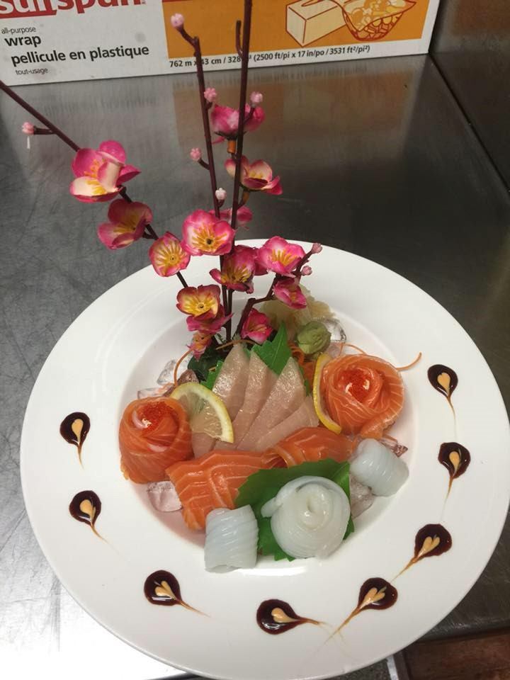 Assorted sashimi with floral garnish and sauce accents on a white plate