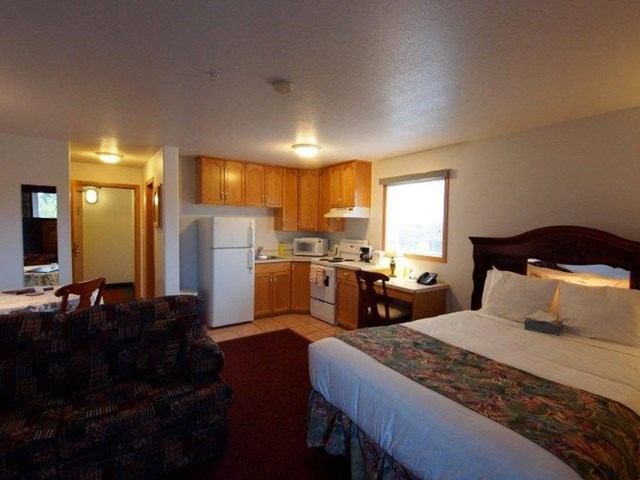 Hotel suite with bed, sofa, and full kitchenette including fridge and stove.