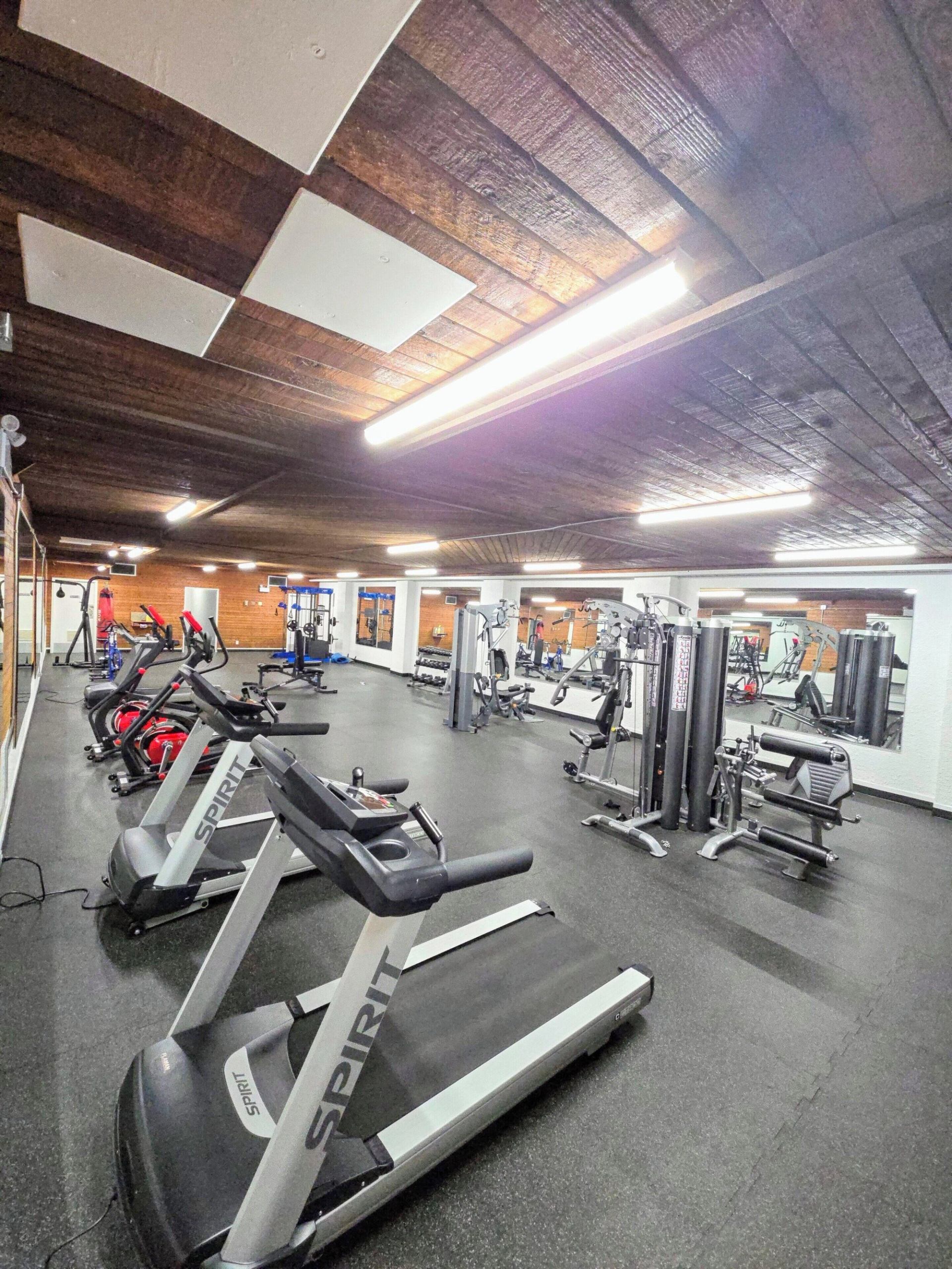 A gym featuring multiple treadmills, cardio machines, and weight equipment.