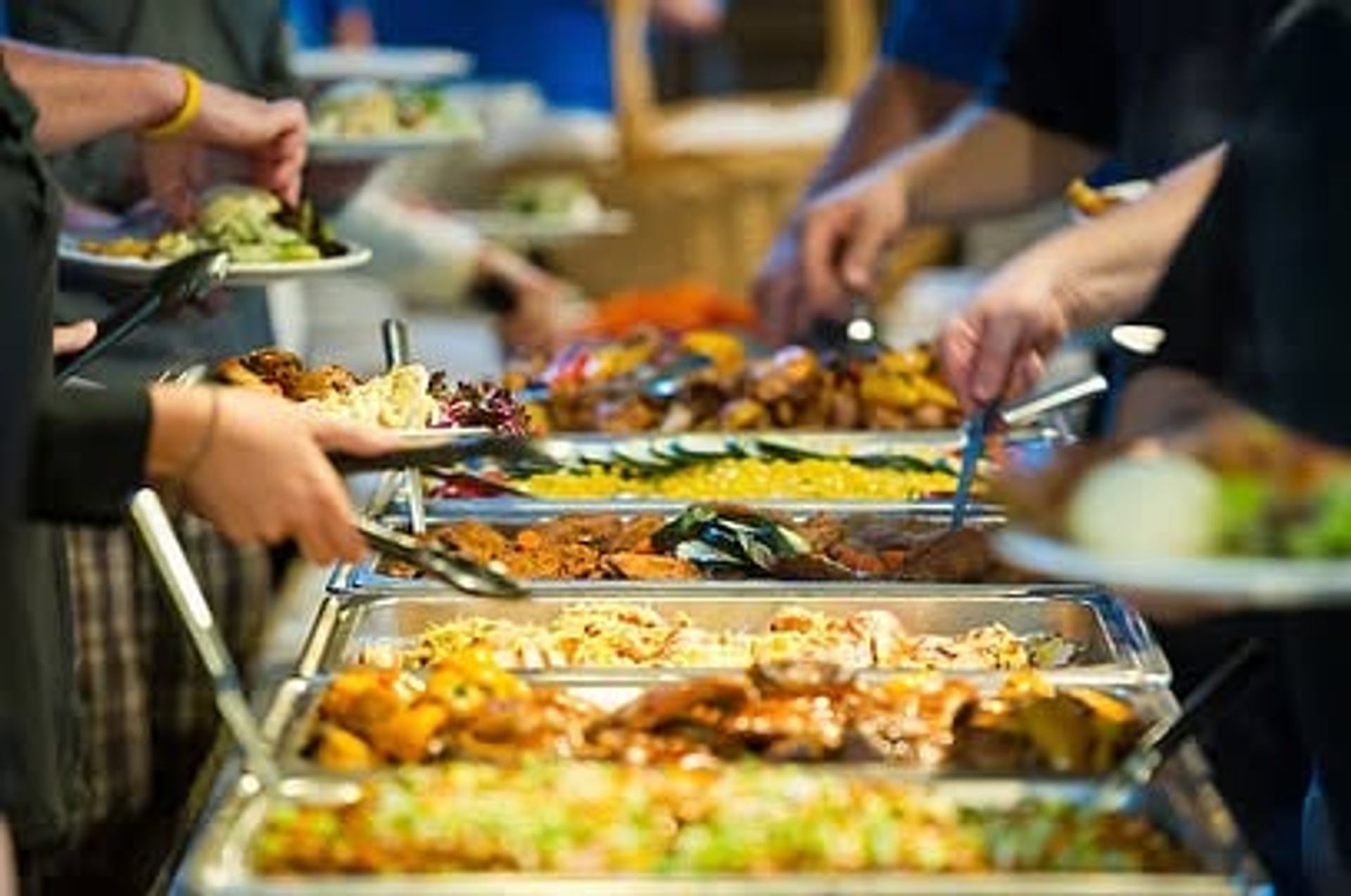 Guests serve themselves from a buffet featuring a variety of hot dishes and fresh food options.