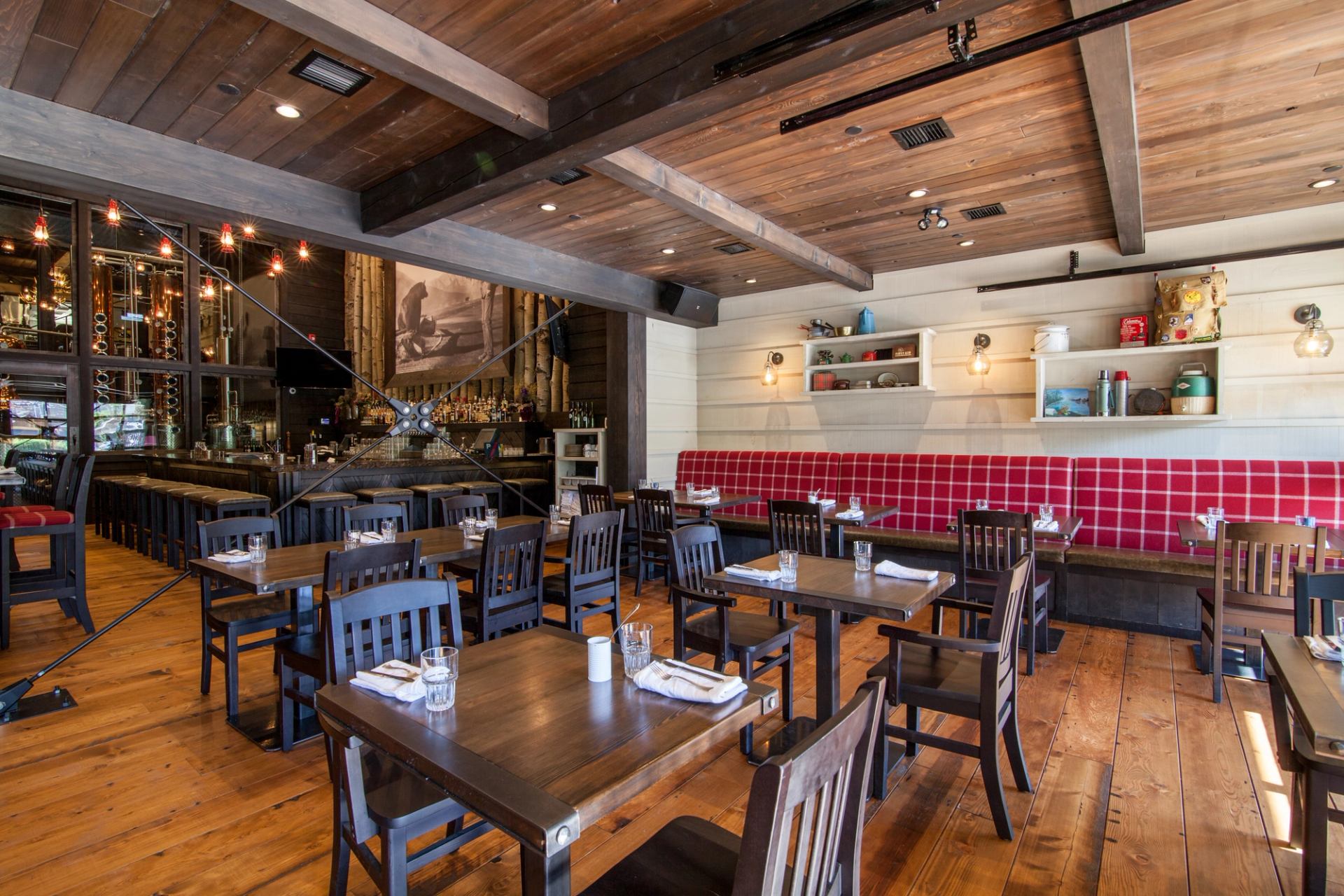 Rustic restaurant interior with wooden floors, ceiling, and beams, dark wood tables and chairs.