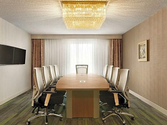 Conference room at The Landing with table, chairs, chandelier, TV, and large window.
