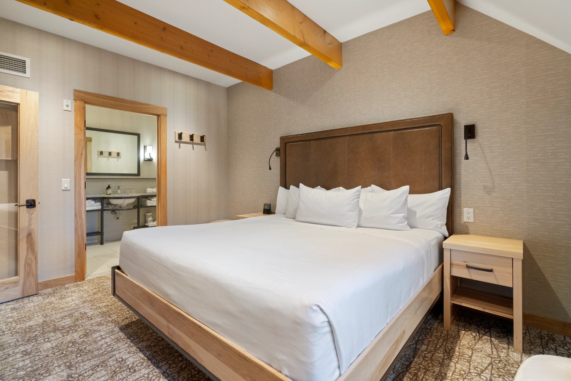 King size bed with wood beams on the ceiling and an ensuite bathoom