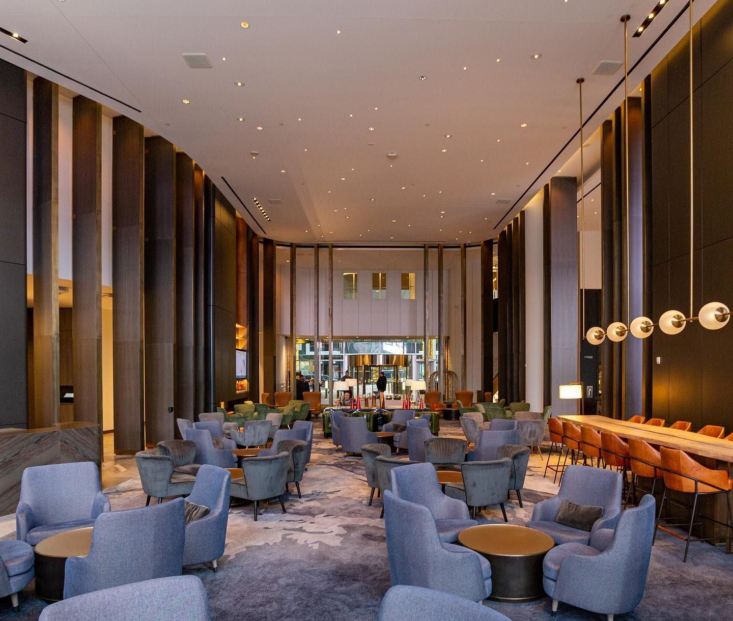 Spacious lounge with plush chairs, bar seating, and modern lighting design