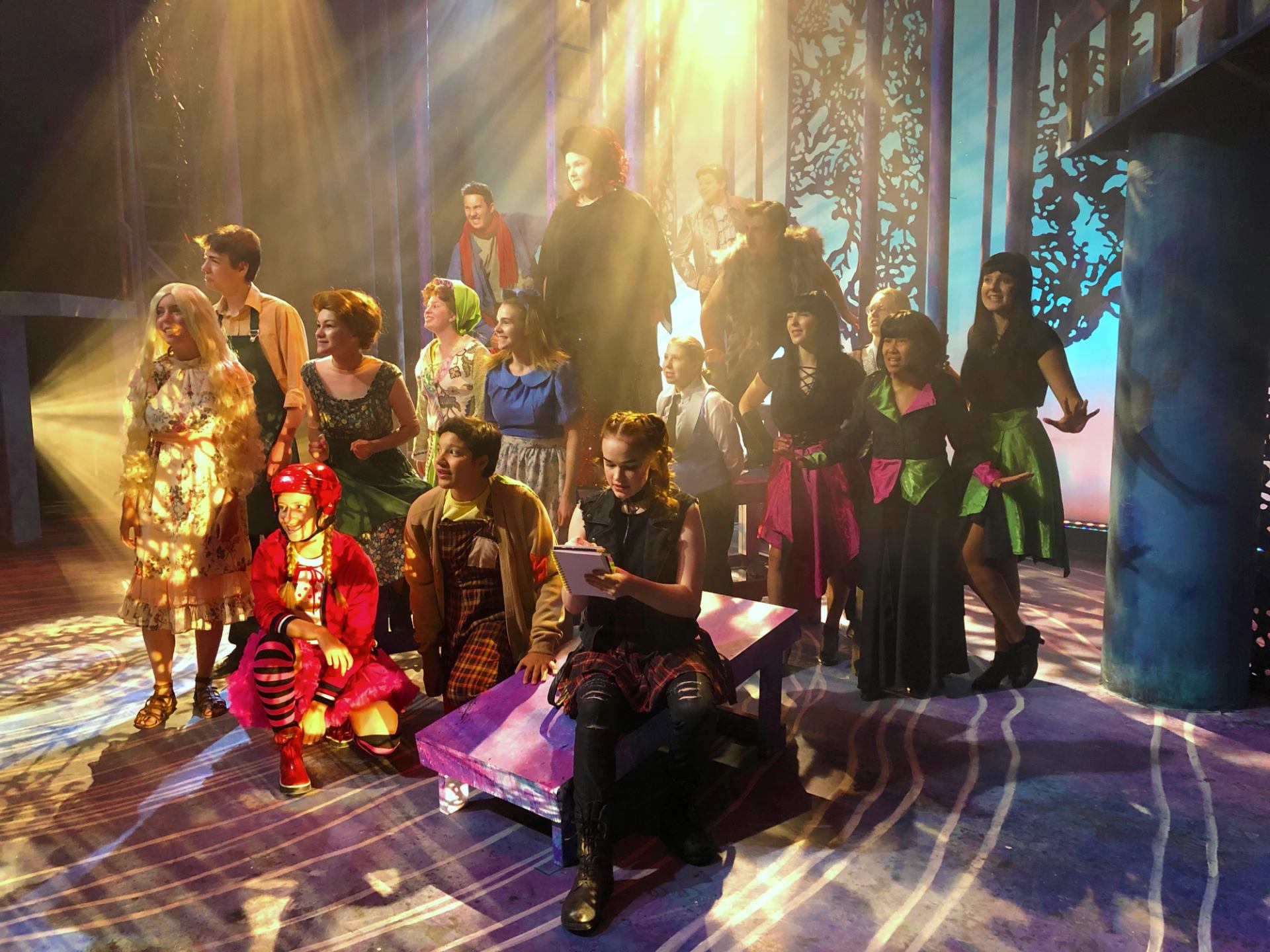 Cast in colorful costumes on stage at Storybook Theatre with dramatic lighting.
