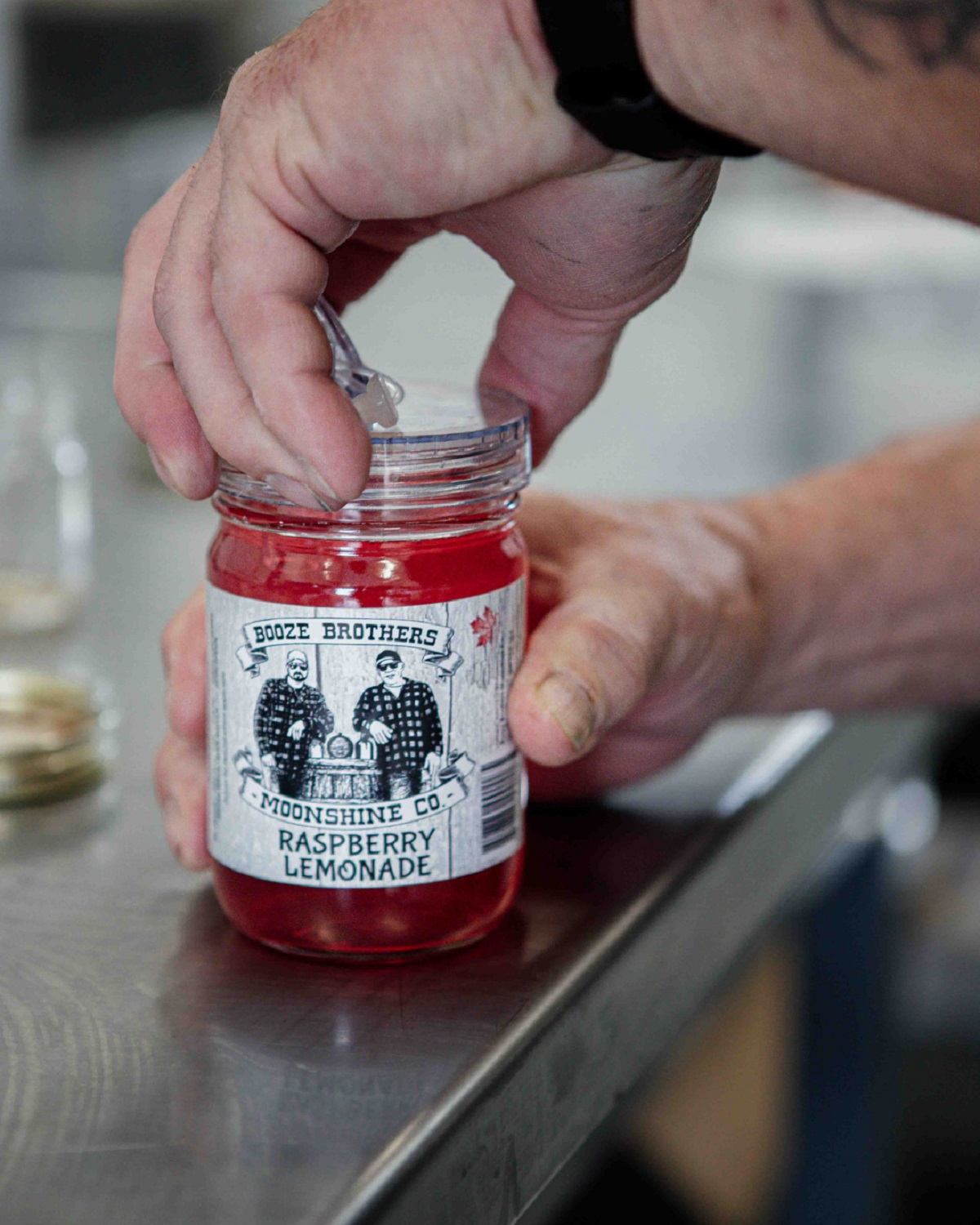 One of the booze brothers putting the lid on a jar of moonshine.