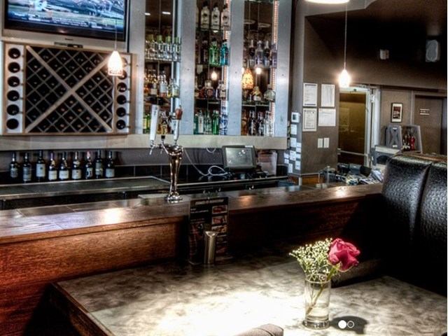 Stylish bar with liquor shelves, wine rack, and cozy seating at Jax Grill and Lounge.