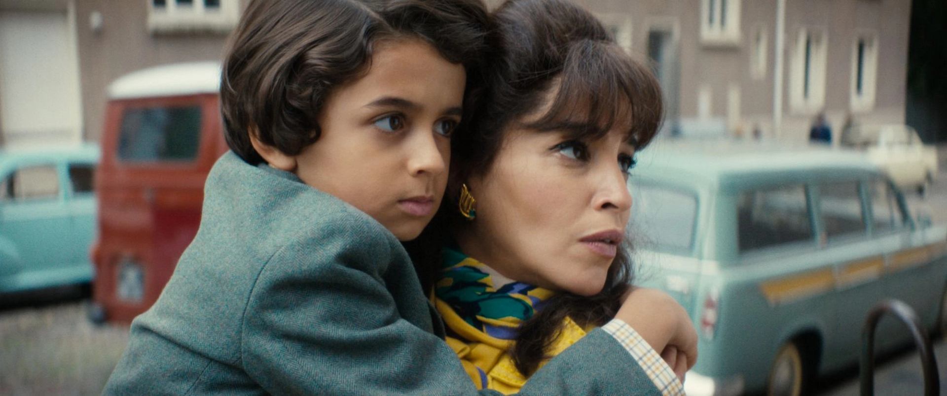 Adult holding child closely in urban setting for Reel Time: Once Upon My Mother.