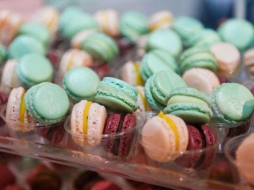Assorted pastel macarons arranged in clear plastic trays on a display.