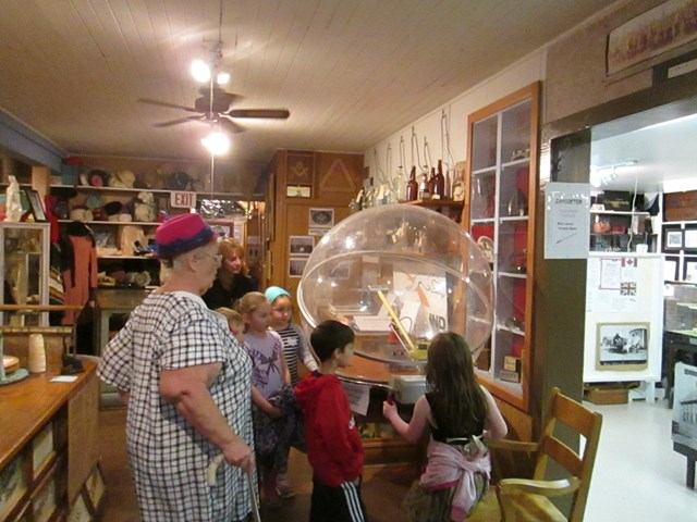 Children and an adult exploring exhibits inside Holden Historical Society Museum.
