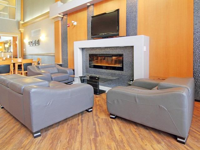 Modern lounge with gray sofas, fireplace, and TV at Holiday Inn Express Calgary South.
