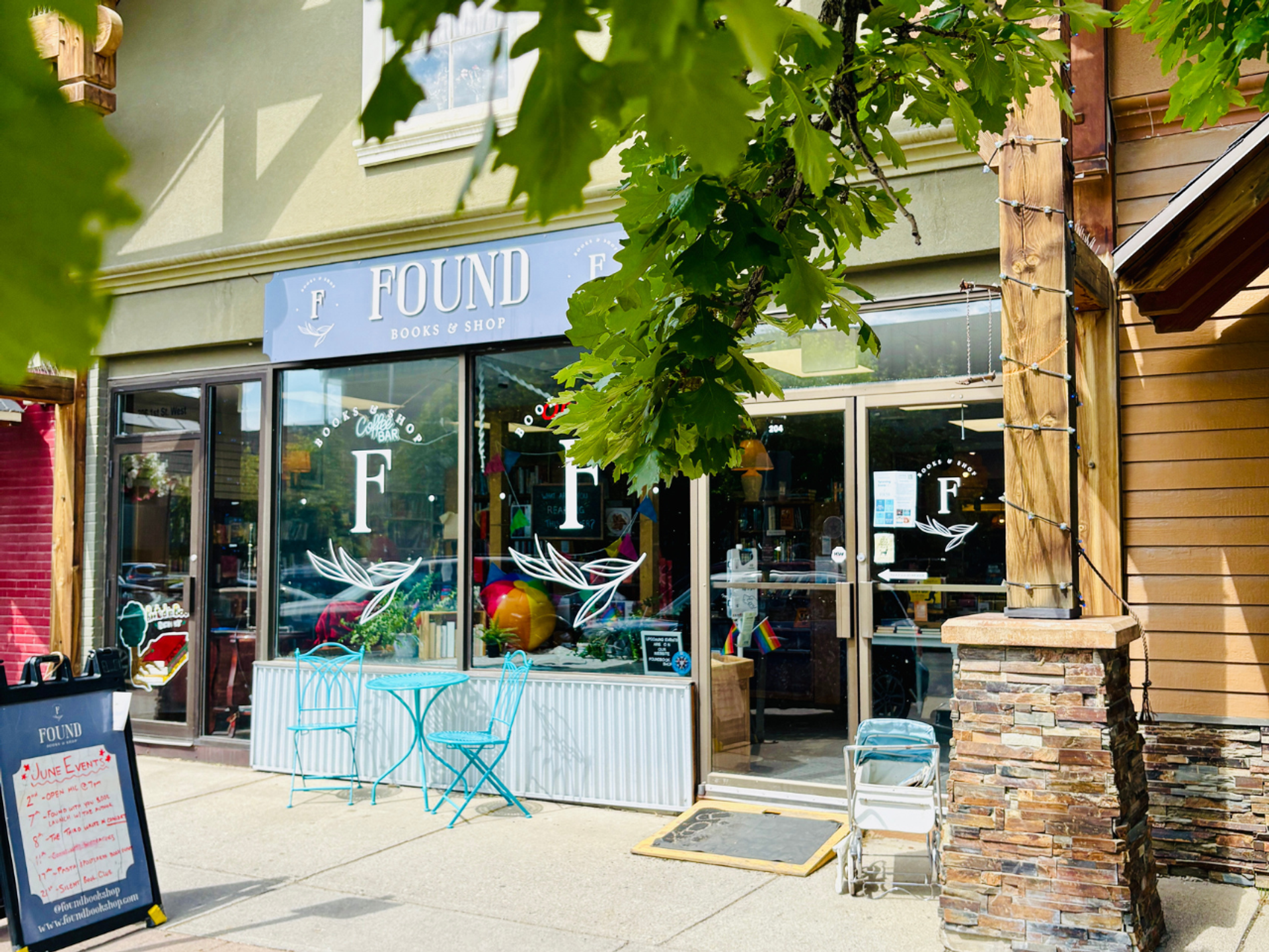 bookstore store front from the street looking in with green trees in the forefront
