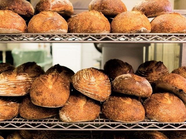Freshly baked loaves of bread stacked on metal racks.