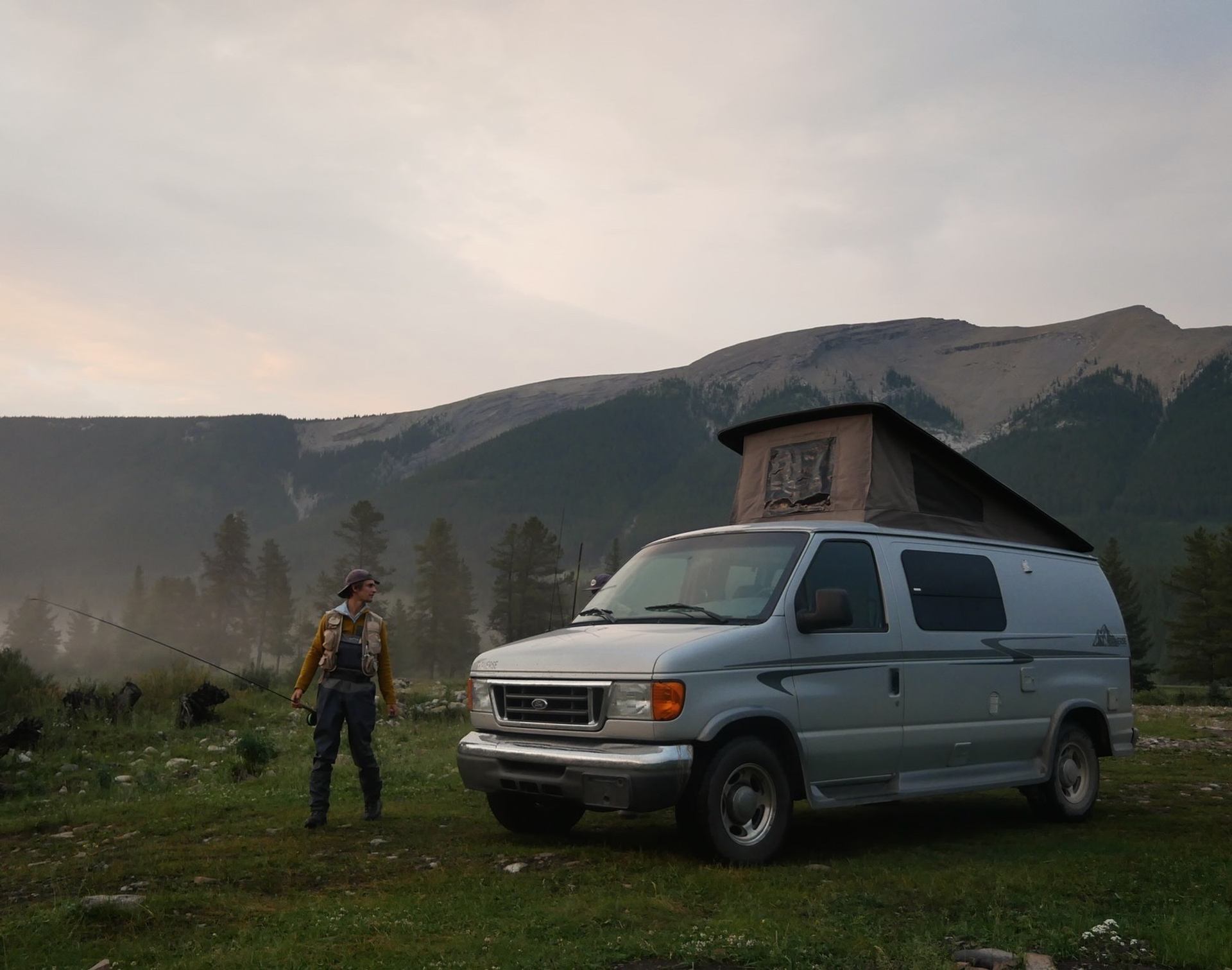 Camper van with pop-up roof in mountain setting.
