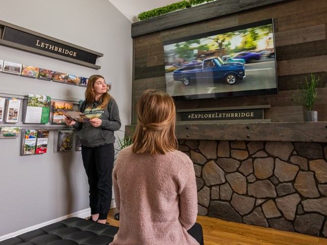 Two visitors watching an television inside the Visitor Information Centre.