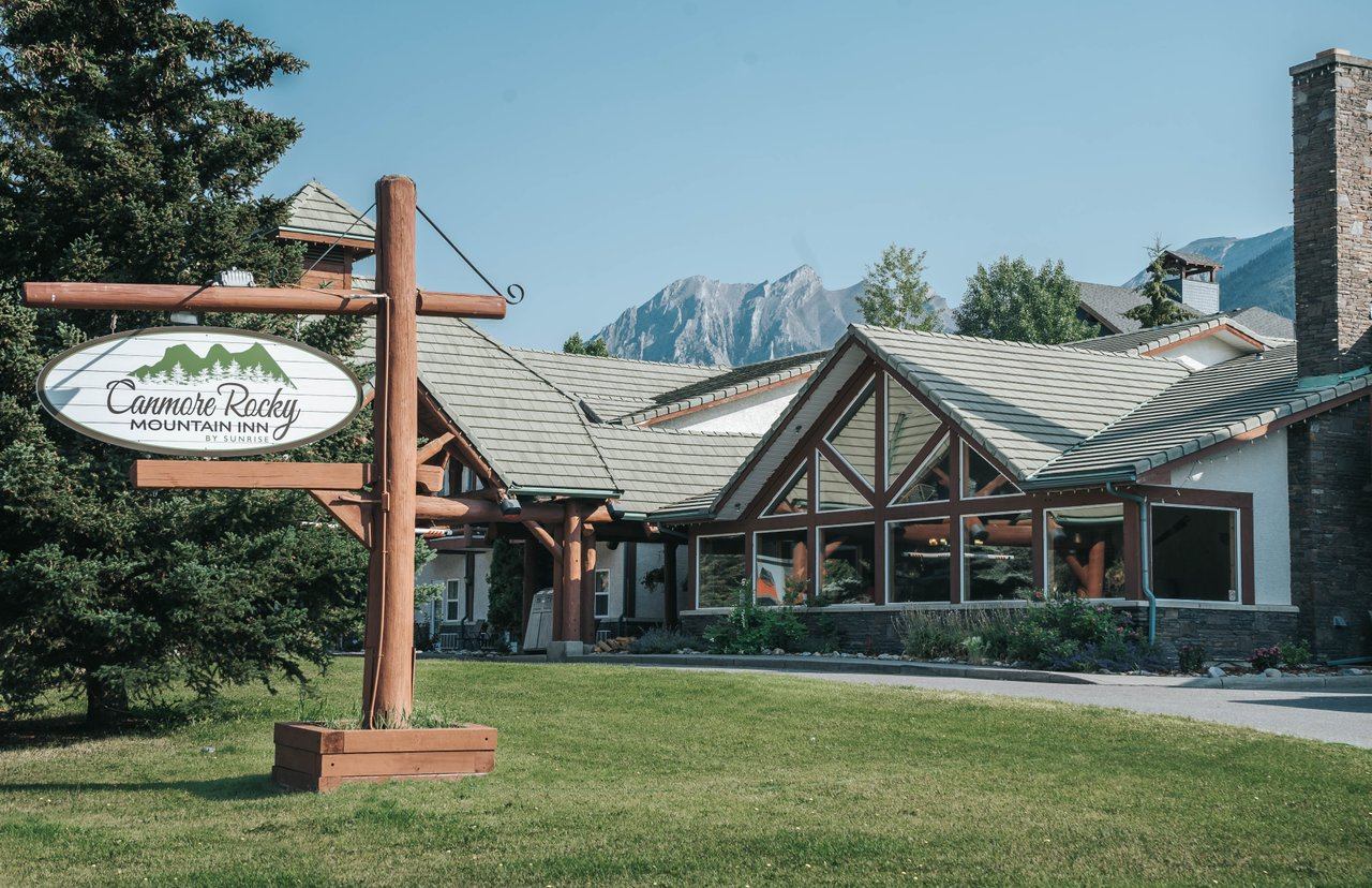 Canmore Rocky Mountain Inn sign in front of a lodge-style building with mountains in the background.