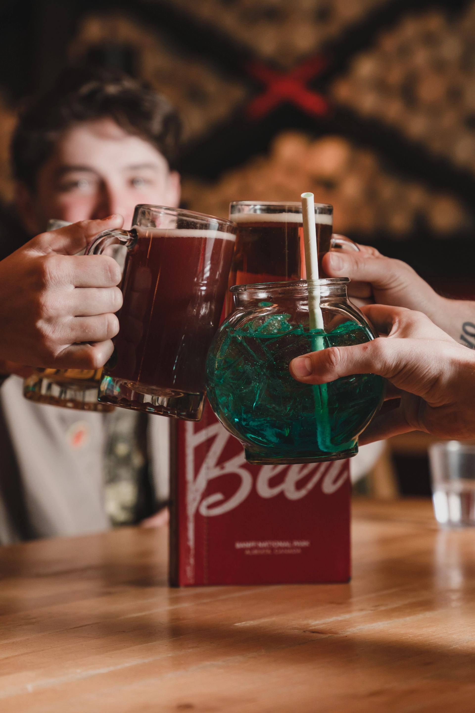 A group cheers with pints of beer and a king pin fishbowl.