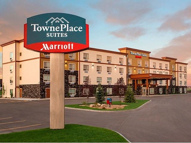 Modern hotel exterior with TownePlace Suites sign and landscaped entrance.
