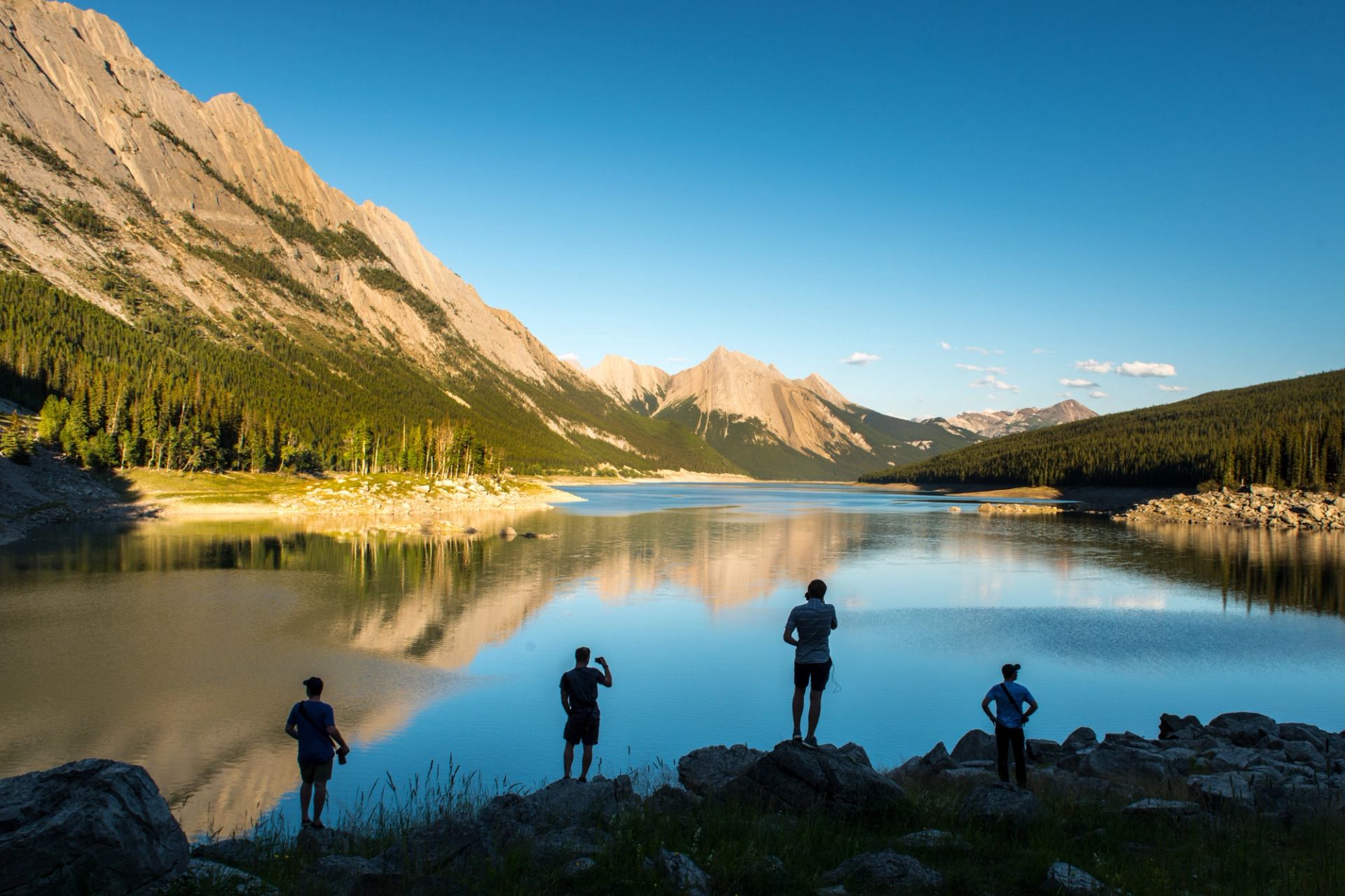 People looking out onto Medicine Lake with the Rocky Mountains in the background.