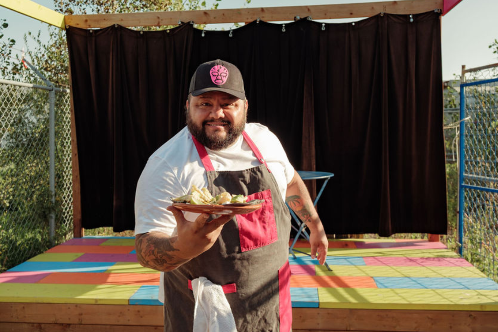 Contestant with hot sauce dish on vibrant stage.