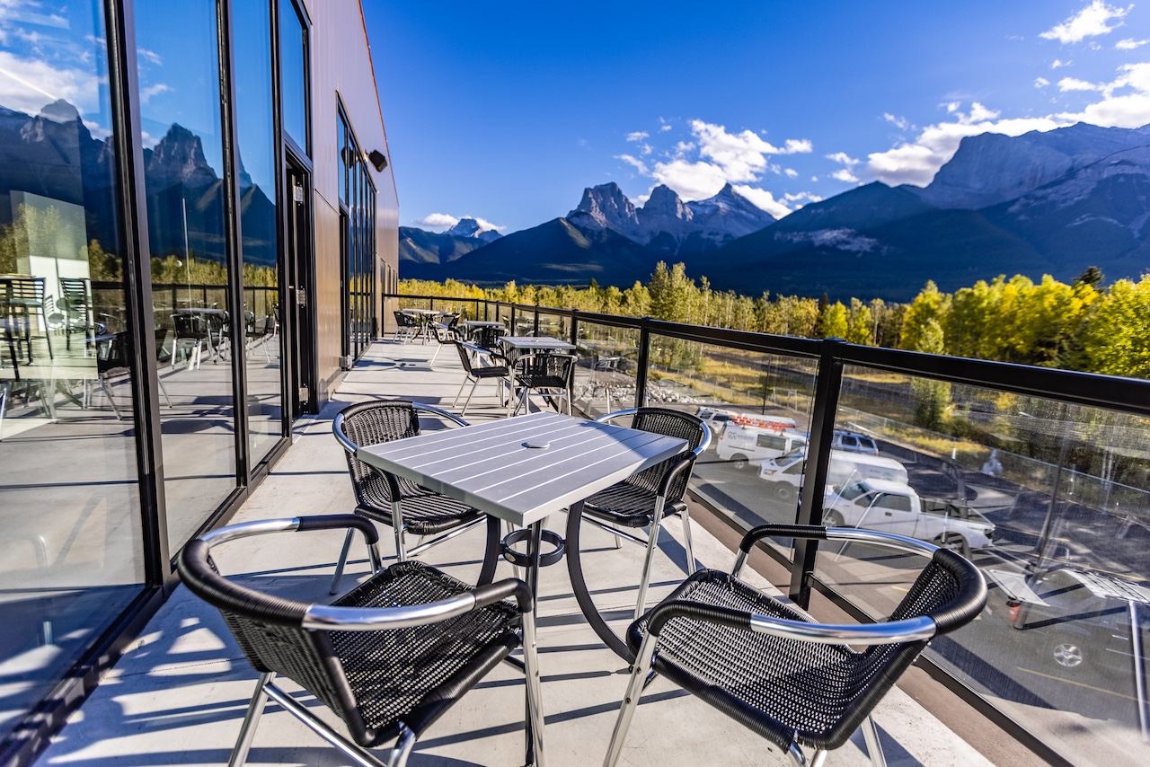 Patio tables on a balcony facing a panoramic mountain range