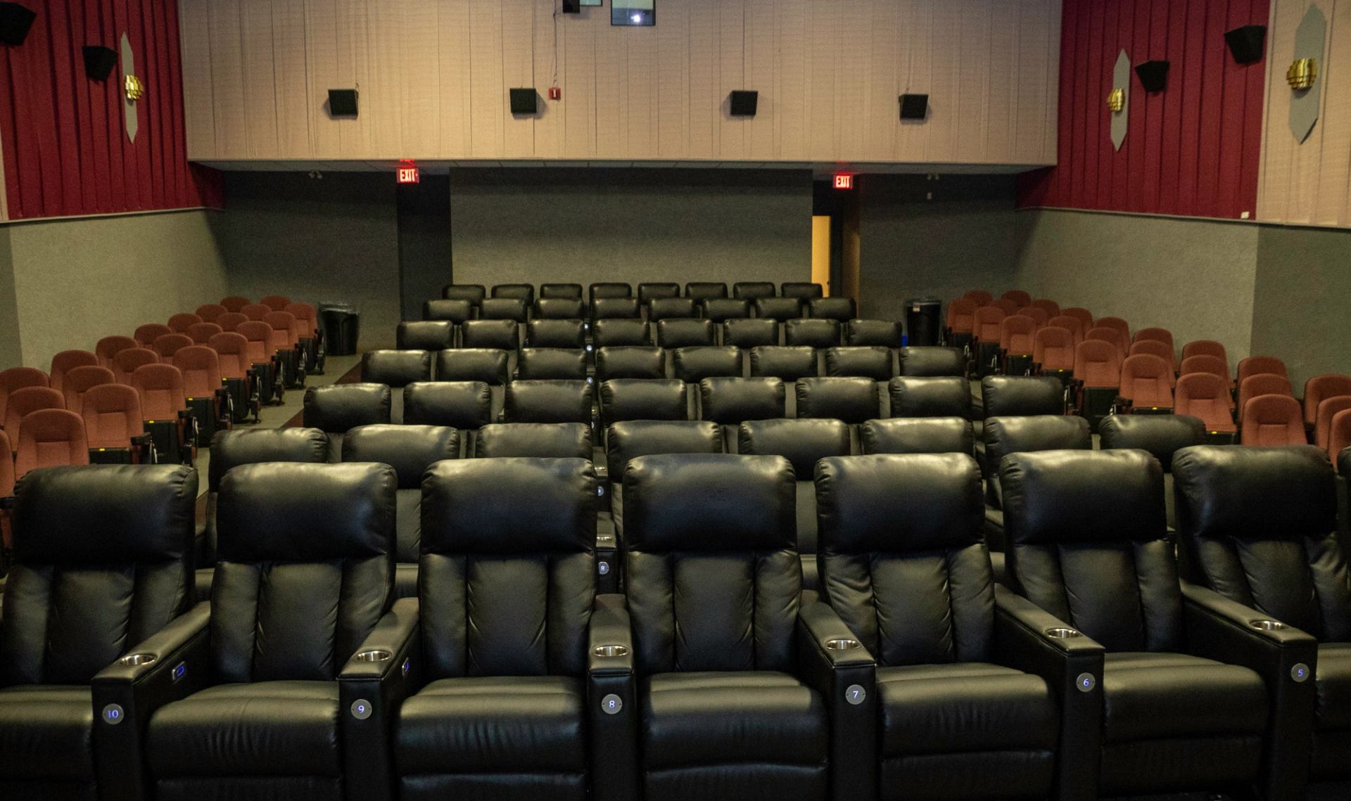 Movie theater with recliner and red fabric seats, red curtains, and front screen.
