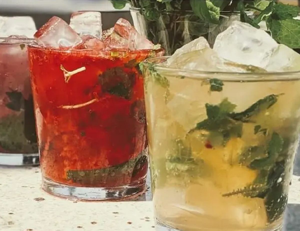 Two iced cocktails with mint leaves in clear glasses on a vibrant table.