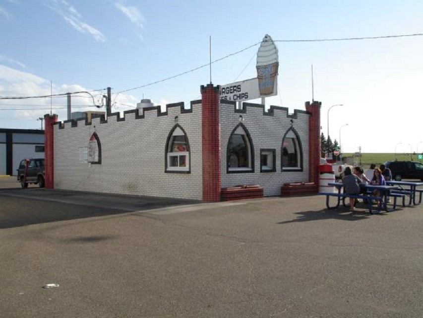 White brick drive-in with arched windows, ice cream cone sign and people at picnic tables.